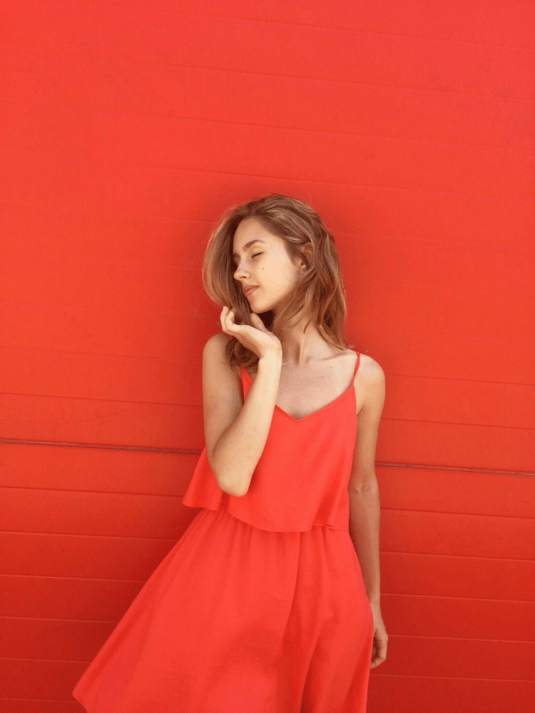 a lady in a red dress against a red wall.